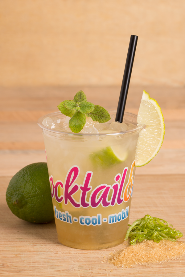 Abbildung des Cocktails: Durchsichtiger Cocktail mit Eiswürfeln in Plastikbecher mit Cocktailooo-Logo. Verziert mit braunem Zucker, Limetten und Zitronen.