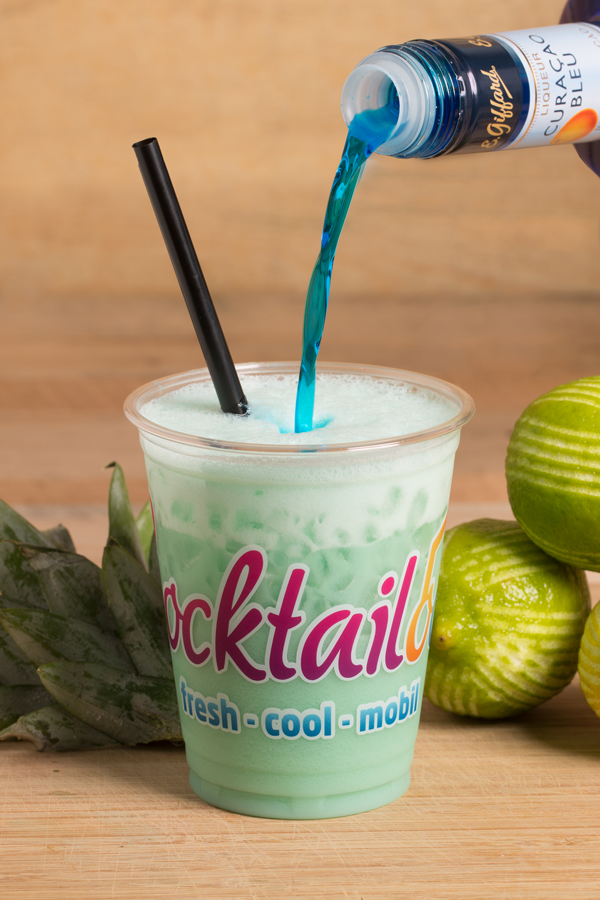 Abbildung des Cocktails: Grün-Weißer Cocktail in Plastikbecher mit Cocktailooo-Logo. Verziert mit Limette. 
